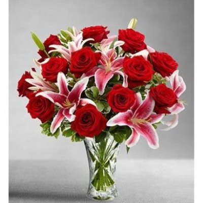 Arrangement of red roses and pink lilies in a clear glass vase