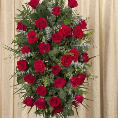 Standing spray of red roses arranged in an oval shape on an easel