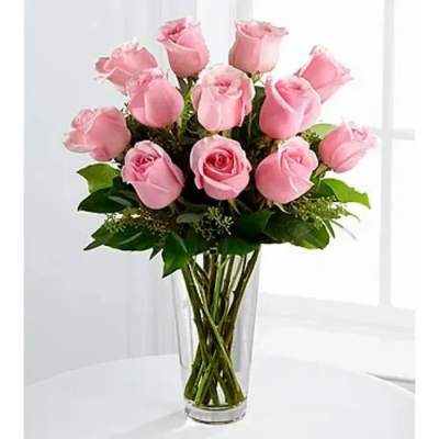 Tall clear glass vase filled with a dozen light pink roses