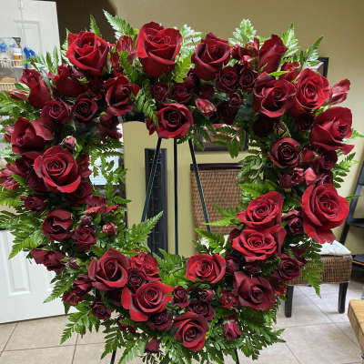 Heart-shaped wreath of red roses on a stand