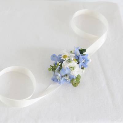 Small blue and white floral wrist corsage with ribbon