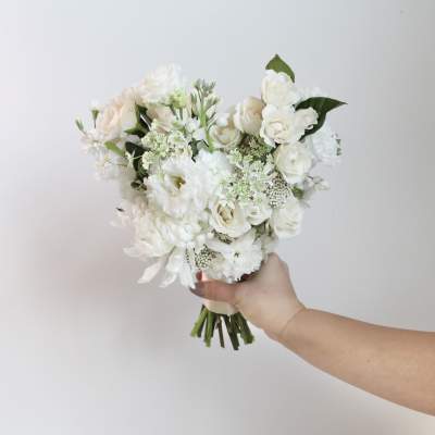 White bouquet of roses and mixed blooms held in one hand