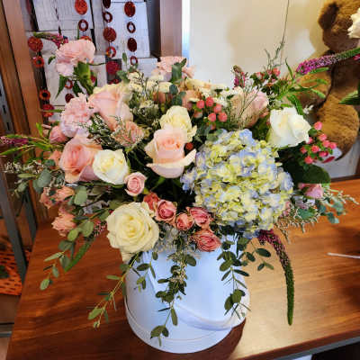 Mixed bouquet of pink and white roses with blue hydrangea in a white vase