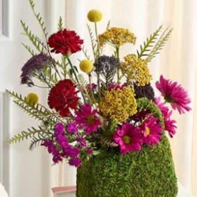 Colorful mixed flower arrangement in a moss-covered square container