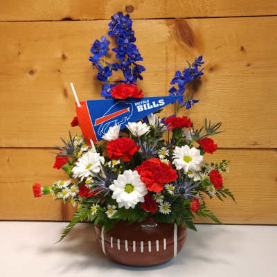 Football-themed flower arrangement in a football-shaped container with red, white, and blue flowers