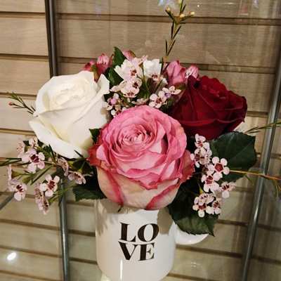 Pink, white, and red roses in a white mug with "LOVE" text