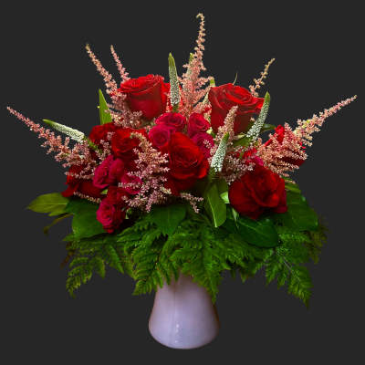 Red roses and pink filler flowers in a white vase