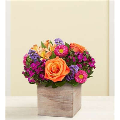 Orange roses and purple flowers arranged in a wooden box