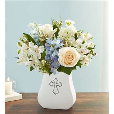 White and blue flower arrangement in a white vase with a cross