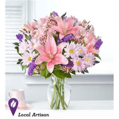 Pink lilies and daisies in a clear glass vase