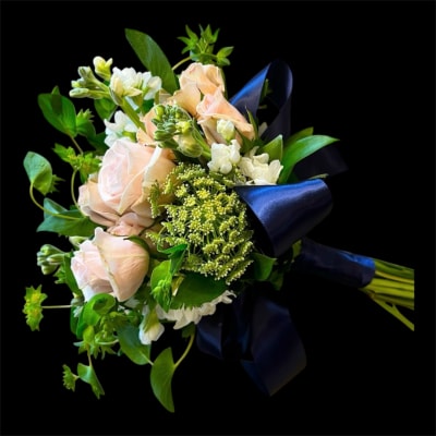 Bouquet of pale pink roses and white flowers with a dark blue ribbon