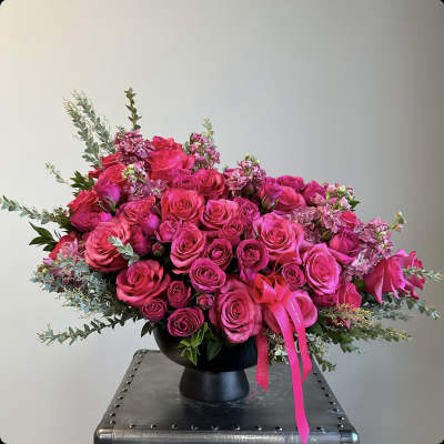Pink rose bouquet in a black vase with ribbon