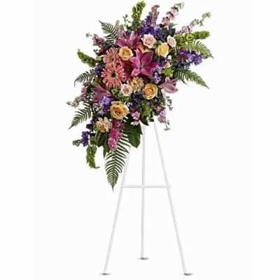 Standing floral spray with pink, purple, and peach flowers on a white easel