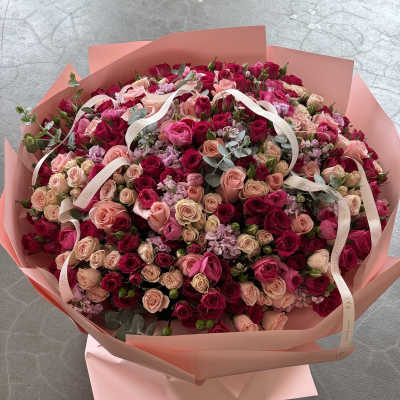 Large bouquet of pink and red roses wrapped in blush paper