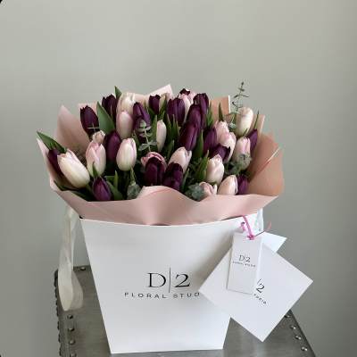 Bouquet of pink and deep purple tulips in a white box