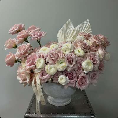 Pink and white rose arrangement in a gray urn vase