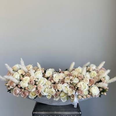 Low arrangement of cream and blush roses in a gray container