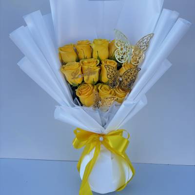 Bouquet of yellow roses wrapped in white paper with a yellow ribbon