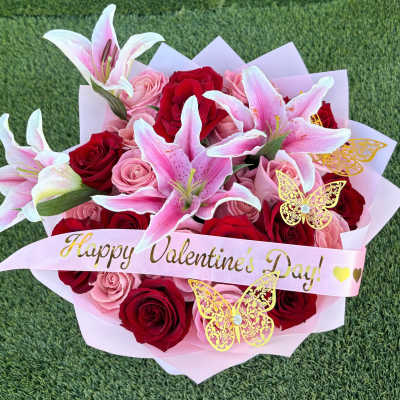 Bouquet of red and pink roses with pink lilies and a Valentine ribbon