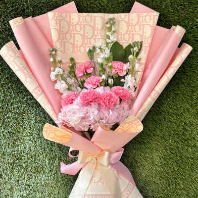 Pink and white bouquet with carnations and hydrangea wrapped in patterned paper