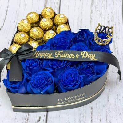 Blue roses and gold-wrapped chocolates in a heart-shaped gift box