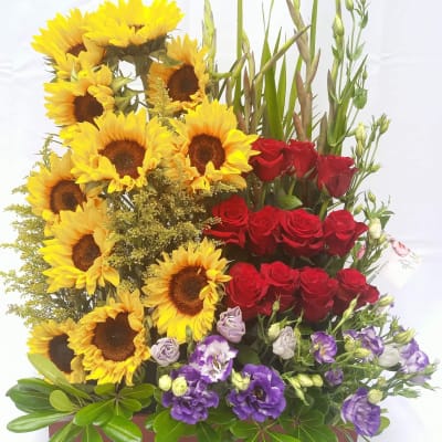 Sunflowers, red roses, and purple blooms in a rectangular planter