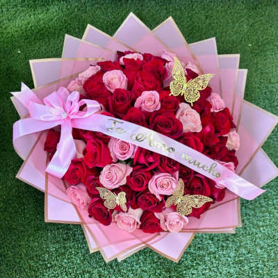 Bouquet of red and pink roses wrapped in pink paper with a ribbon
