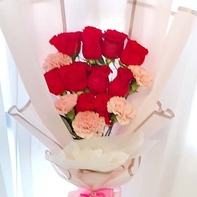 Bouquet of red roses and pale pink carnations wrapped in blush paper