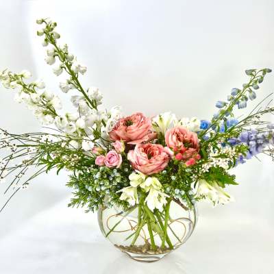 Mixed floral arrangement in a round glass vase with pink and white blooms