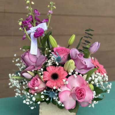 Pink and lavender bouquet with roses, gerbera daisy, and lilies in a wooden box