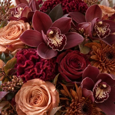 Bouquet of burgundy orchids, peach roses, and orange chrysanthemums