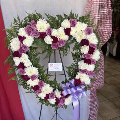 Heart-shaped floral wreath with pink roses and white chrysanthemums on an easel