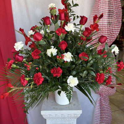 Tall red and white floral arrangement in a white pot