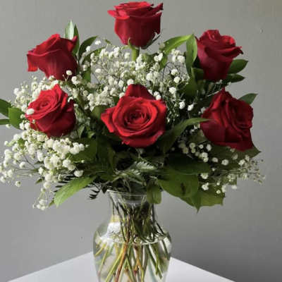 Red roses and baby's breath arranged in a clear glass vase