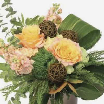 Yellow roses and pink flowers arranged in a brown vase with greenery