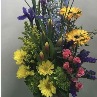 Tall mixed flower arrangement in a birch bark container with yellow, purple, pink, and blue blooms