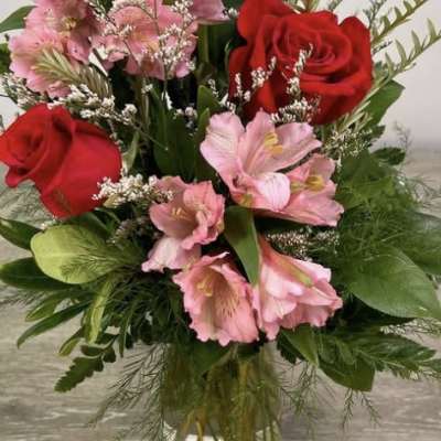 Bouquet of red roses and pink flowers in a clear glass vase