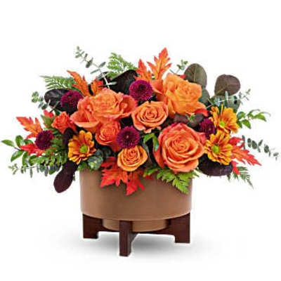 Orange roses and dark mums in a low brown container