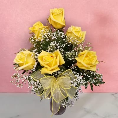Yellow roses in a vase with baby's breath and a yellow ribbon bow