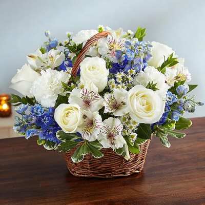 White roses and blue flowers arranged in a wicker basket