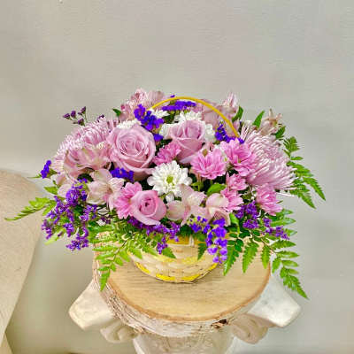 Pink roses and mixed daisies in a woven basket
