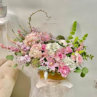 Pink and white floral arrangement in a gold box with arching branches