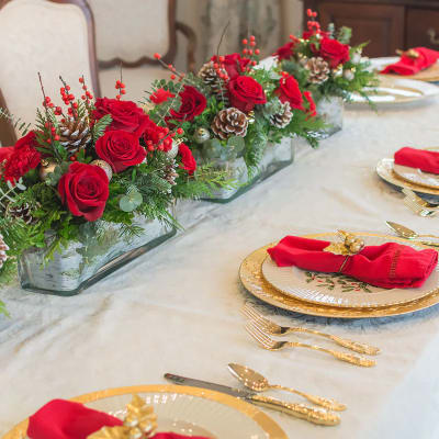 Red rose centerpieces in low glass containers on a set dining table