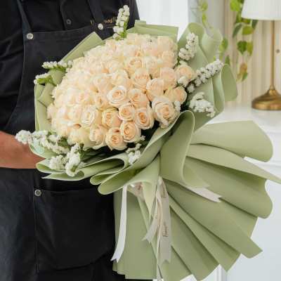 Large bouquet of pale peach roses wrapped in light green paper
