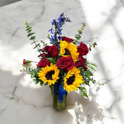 Bouquet of red roses and yellow sunflowers in a glass vase