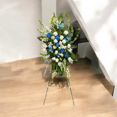 Tall floral standing spray with white and blue flowers on a metal easel