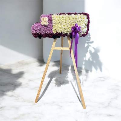 Rectangular floral standing spray on a wooden easel with purple ribbon