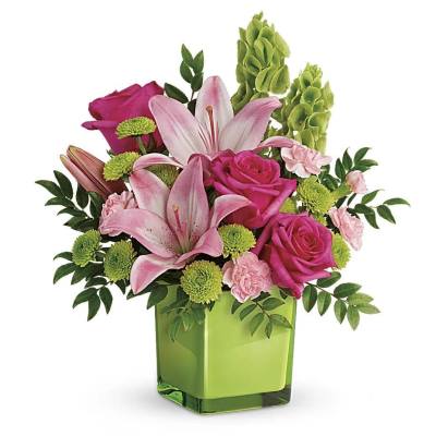 Pink lilies, roses, and green mums arranged in a bright green cube vase