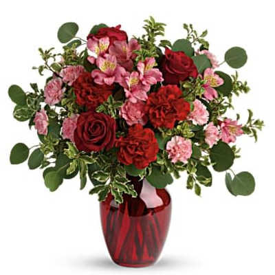 Red and pink flower bouquet in a red glass vase