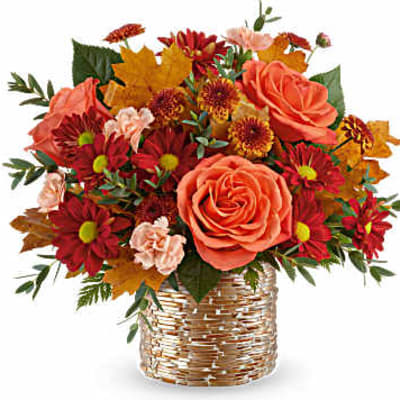 Bouquet of orange roses and red daisies in a woven basket
